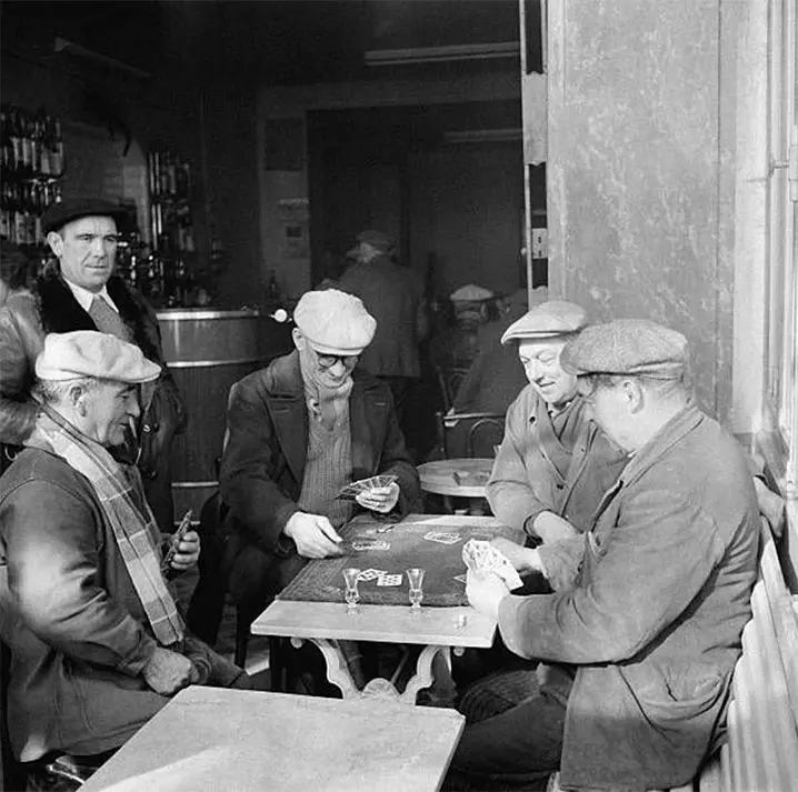 Groupe de personnes jouant à la belote autour d'une table dans un bar