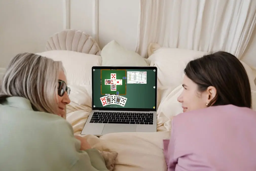 Deux personnes devant un écran, découvrant ensemble le jeu de belote
